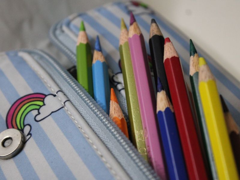 colorful pencils in a striped pencil case product photo
