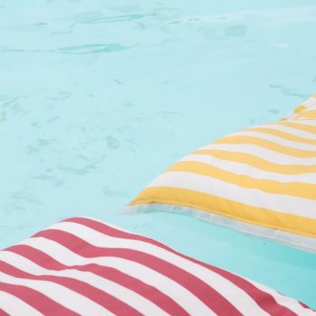 colorful striped pool floats on crystal clear blue pool water
