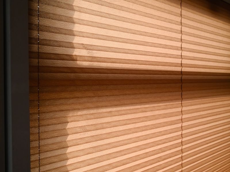 sunlight casting warm shadows through closed window blinds