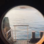 View through a ship porthole window to the ocean hero image