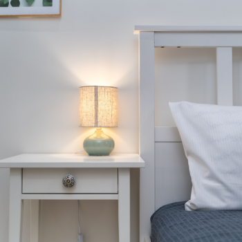 Cozy dorm-style bedroom nightstand and bed scene hero image