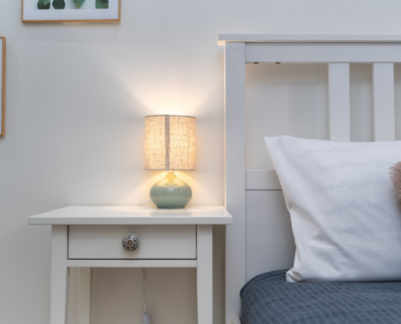 Cozy dorm-style bedroom nightstand and bed scene hero image