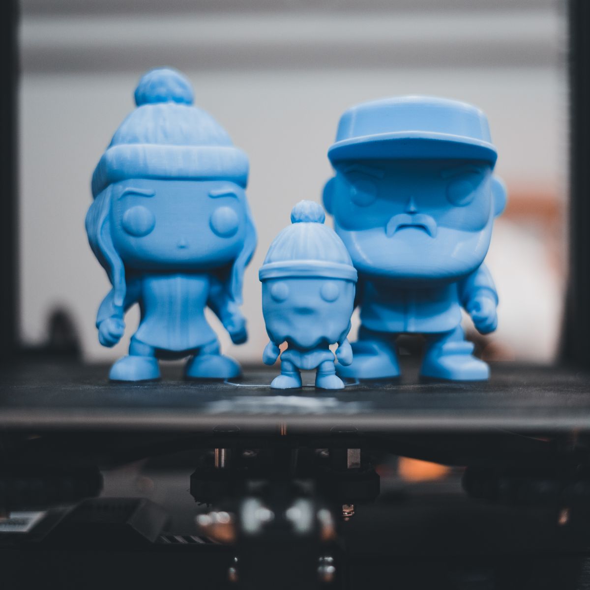 blue 3D printed figurines on a printer bed product photo