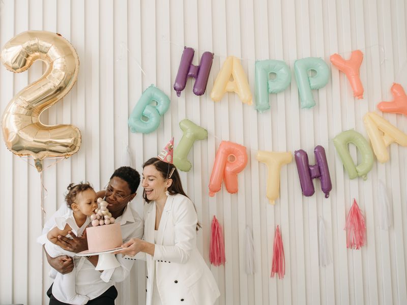 family celebrating a birthday party with balloon letter garland