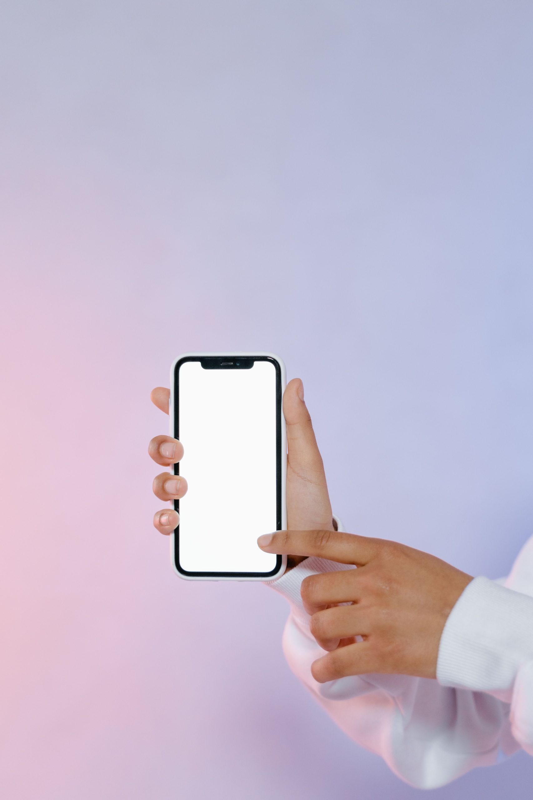 Two hands holding a smartphone with a blank screen, one finger pointing at it