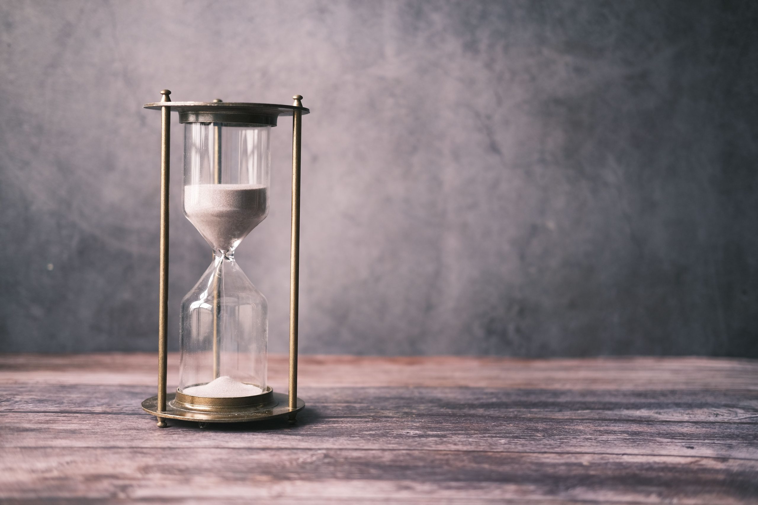 Hourglass with sand running through it on a wooden table, representing setting time limits