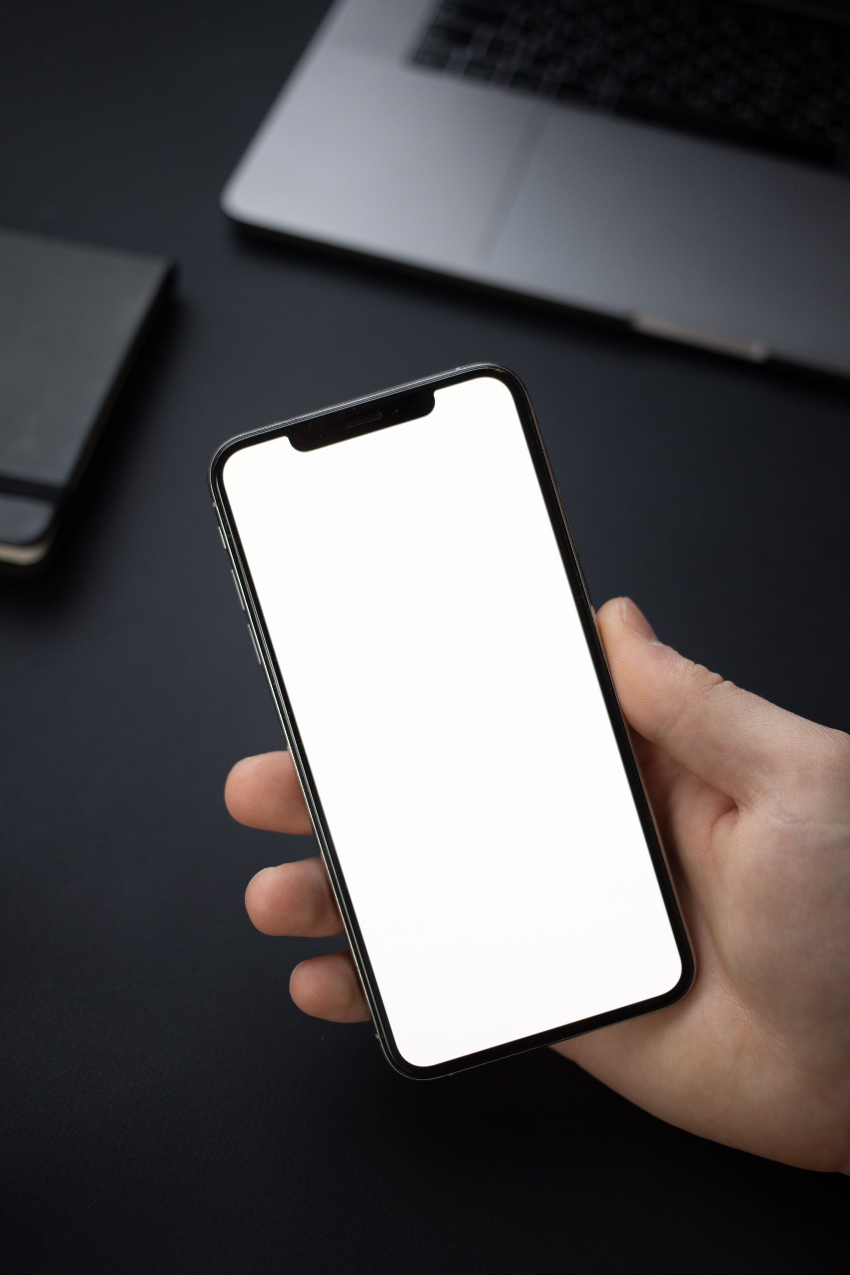 Hand holding a smartphone with a completely blank screen and no notification badges visible