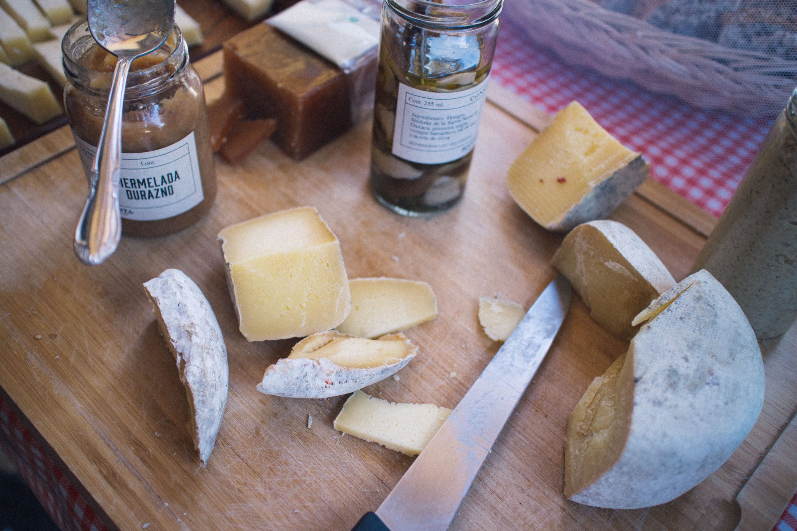 Cheese knife slicing a wedge of cheese on a wooden board