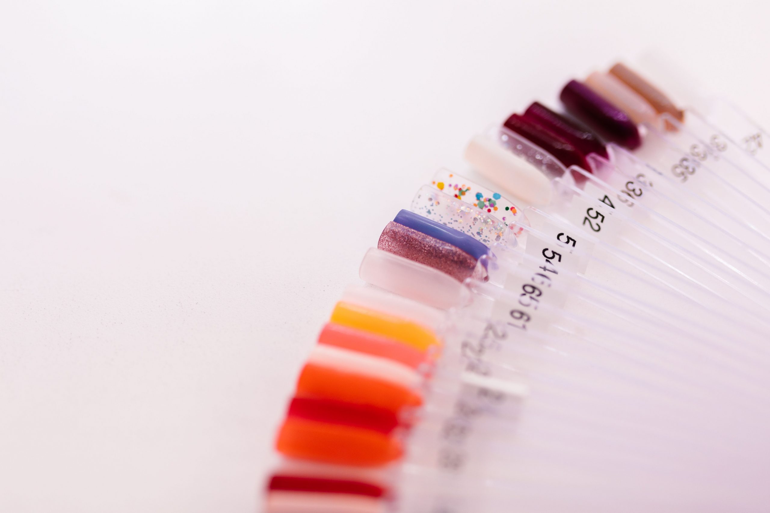 Colorful nail polish samples arranged in a fan on a white background