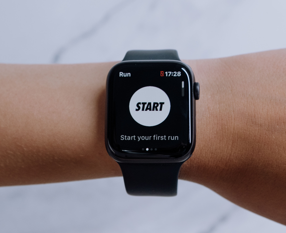 Running watch showing a run-tracking app on a wrist, marble background