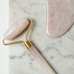 Rose quartz gua sha stone and facial roller on a marble surface, best gua sha and face tools