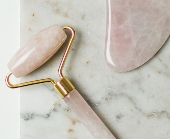 Rose quartz gua sha stone and facial roller on a marble surface, best gua sha and face tools