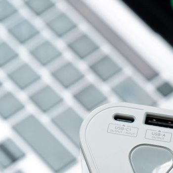 top-10-portable-power-banks-hero-v2 Close-up of a portable power bank with USB-C and USB-A ports near a laptop keyboard, best portable power banks