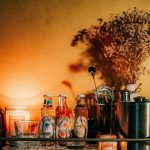 Moody home bar cart styled with bottles, a cocktail shaker, candles, and dried flowers