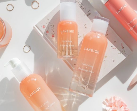 Pastel pink K-beauty flat lay with Laneige skincare bottles, rose quartz roller, and rings, k-beauty essentials