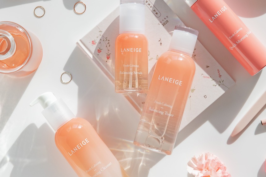 top-10-k-beauty-essentials-hero Pastel pink K-beauty flat lay with Laneige skincare bottles, rose quartz roller, and rings, k-beauty essentials
