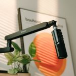 Microphone on a boom arm lit by warm sunlight on a modern streaming desk setup