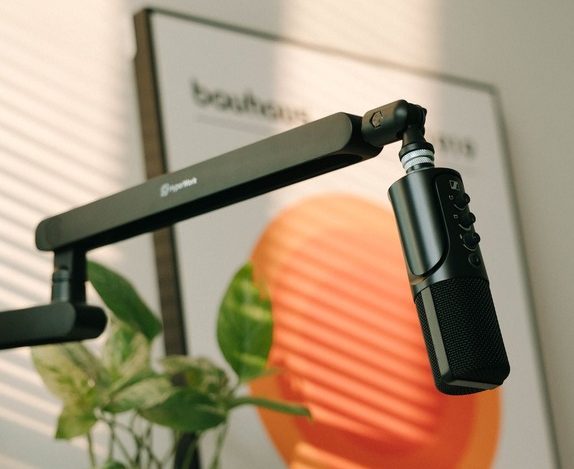 Microphone on a boom arm lit by warm sunlight on a modern streaming desk setup