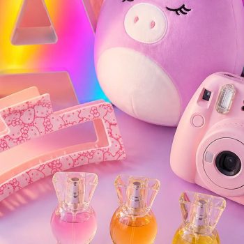 Pastel flat lay of tween girl gifts including a glowing marquee letter A, a Hello Kitty claw clip, a unicorn Squishmallow, a pink Instax camera, and a perfume trio