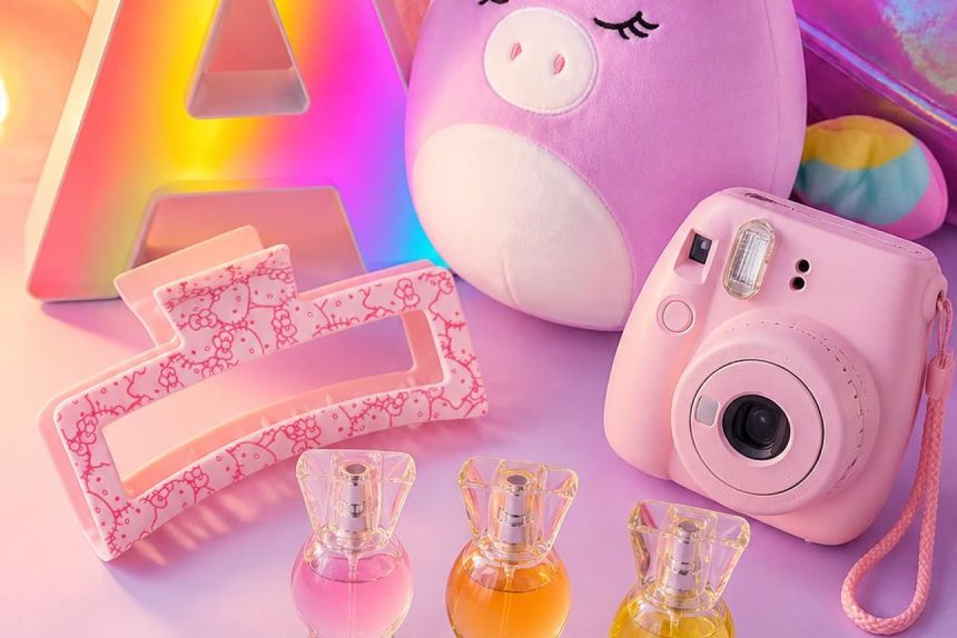top-10-tween-girl-gifts-hero-pin-crop Pastel flat lay of tween girl gifts including a glowing marquee letter A, a Hello Kitty claw clip, a unicorn Squishmallow, a pink Instax camera, and a perfume trio
